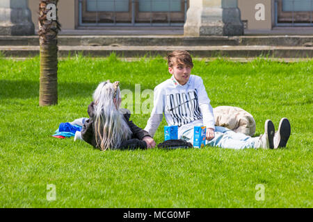 Young couple sitting relaxing on the lawn of Royal Pavilion grounds, Brighton, East Sussex, England UK in April Stock Photo