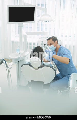 Young male dentist examining his patients teeth Stock Photo