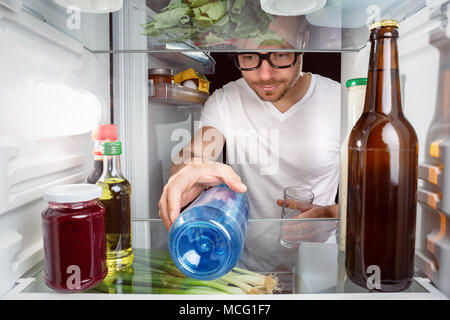 Man grabbing a water bottle in the fridge Stock Photo