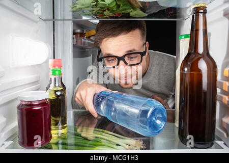 Man grabbing a water bottle in the fridge Stock Photo