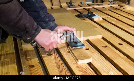 The worker twists the clamping nut on the cnc machine table. CNC milling machine, wood processing. Joinery, furniture and wooden products. Maintenance Stock Photo
