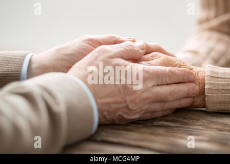 Nice senior man touching his wifes hands Stock Photo