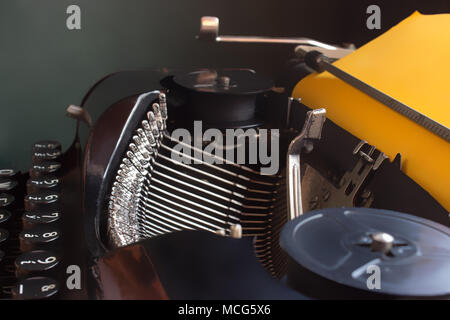 Detail of old typewriter with yellow paper ready for writing - dark background Stock Photo