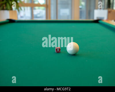 White cue ball and chalk sitting on billiards table ready for pool Stock Photo