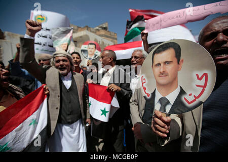 Sanaa, Yemen. 16th Apr, 2018. Yemeni protesters hold up pictures of Syrian President Bashar al-Assad and wave Syrian flags during a protest in support of the Syrian regime against US, Britain and France's air strikes on Syria, in front of the Syrian embassy in Sanaa, Yemen, 16 April 2018. Credit: Hani Al-Ansi/dpa/Alamy Live News Stock Photo