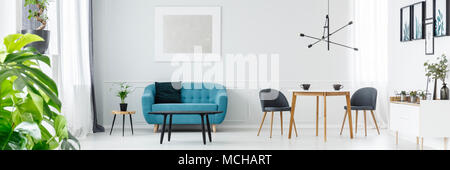 Two coffee cups on a wooden table in white living room interior with blue couch and silver painting on the wall Stock Photo
