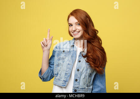 Lifestyle Concept: Happy excited cuacaisan tourist girl pointing finger on copy space isolated on golden yellow background Stock Photo