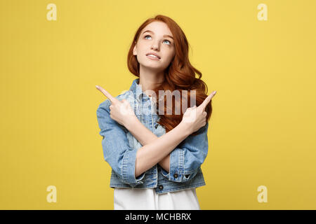 Lifestyle Concept: Happy excited cuacaisan tourist girl pointing finger on copy space isolated on golden yellow background Stock Photo