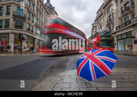 London, England - British umbrella at busy Regent Street with iconic red double-decker buses on the move