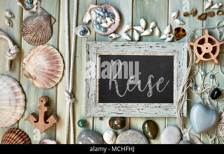 Blackboard With Maritime Decorations on light wood, text in German. 'Reise' means 'Vacations'. Stock Photo