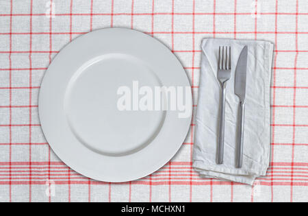 Empty dish and cutlery on red white kitchen towel. Stock Photo