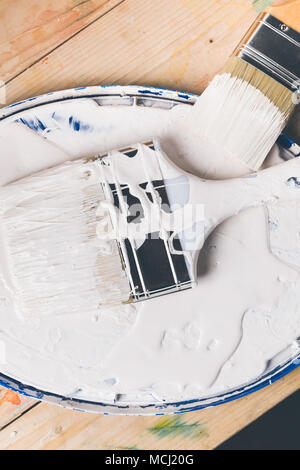 top view of brushes in white paint on cover from bucket Stock Photo