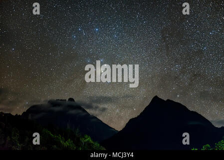 Antares rising in between Mt Kinabalu and Mt Nungkok. Long exposure and high ISO photograph with visible grain and noise, soft focus and motion blur Stock Photo