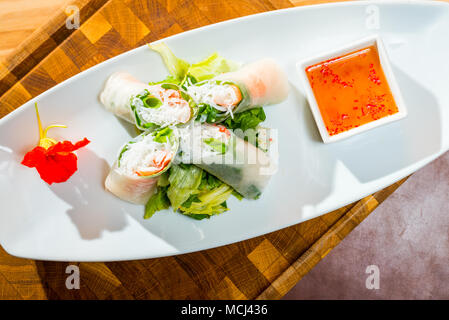 Vietnamese spring rolls with rice pasta on a plate with sauce and vegetables shot close-up Stock Photo
