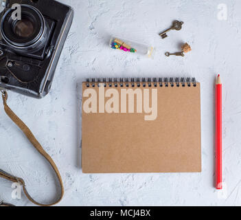open blank notepad on an iron spring with brown sheets and a red wooden pencil on a white background, top view Stock Photo
