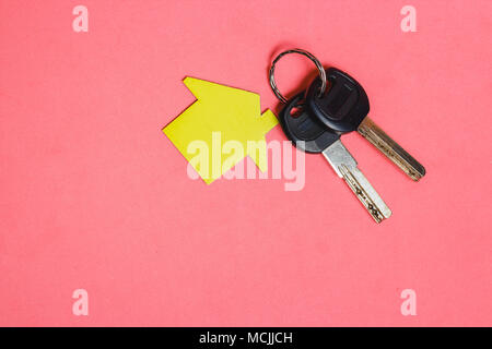 Symbol of House with Two Silver Keys on Pink Background. Concept of Minimalism with Copyspace Stock Photo