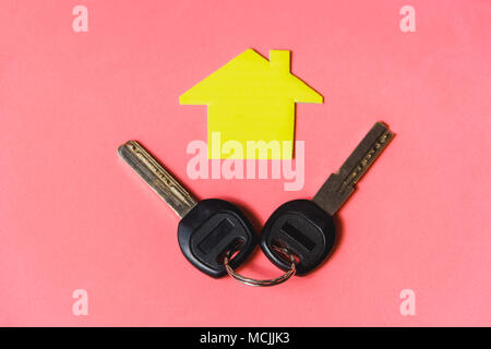 Symbol of House with Two Silver Keys on Pink Background. Concept of Minimalism with Copyspace Stock Photo