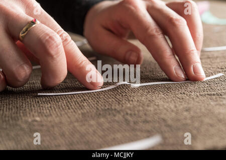 Restoration studio, restorer, hand marking seams for finished support fabric on lent scarf with paper strips, Munich, Bavaria Stock Photo