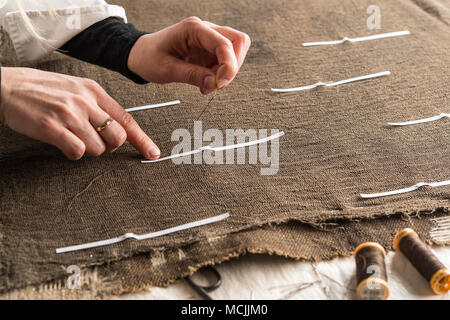 Restoration studio, restorer, hand marking seams for finished support fabric on lent scarf with paper strips, Munich, Bavaria Stock Photo