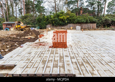 Pile of typical red house bricks stacked on a partly built new housing infill development construction site in southeast England, Surrey, UK Stock Photo