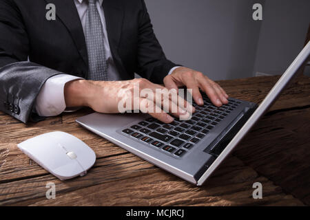 Close-up Of A Businessman's Hand Using Laptop On Wooden Desk Stock Photo