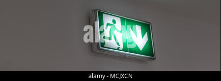 Emergency exit sign in a building glowing green Stock Photo