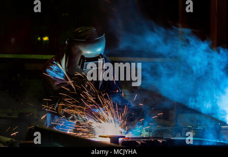 Worker is welding automotive part in car factory Stock Photo