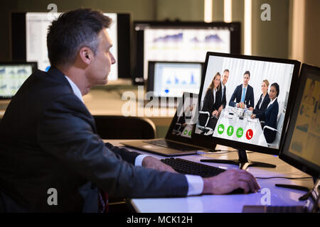 Side View Of A Businessman Video Conferencing With Happy Colleagues On Computer In Office Stock Photo