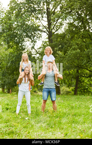 Children ride piggyback on the back of their parents on vacation Stock Photo