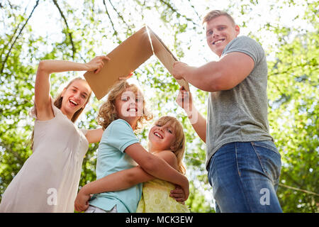 Parents hold umbrella over children as a symbol of protective home Stock Photo
