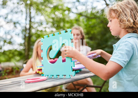Children build a miniature house from colorful puzzle pieces Stock Photo