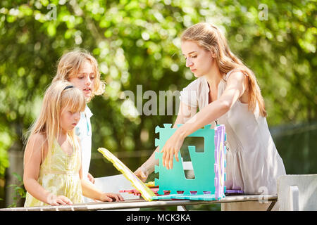 Mother and children play and build a model house with puzzle pieces Stock Photo