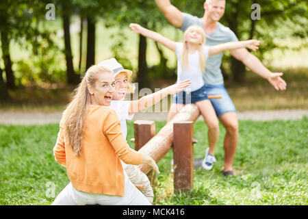 Active family on the playground has a lot of fun together on the swing Stock Photo