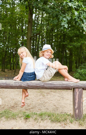 Two children are sitting relaxed in a park in the summer vacation Stock Photo