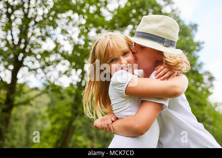 Boy gives his girlfriend a kiss on the cheek in the garden in summer Stock Photo