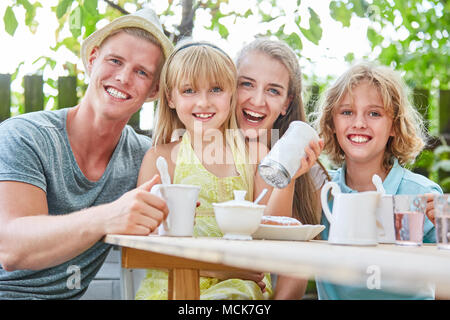 Happy family having coffee in garden with lots of sugar Stock Photo
