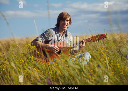 handsome young man with acoustic guitar summer outdoors Stock Photo