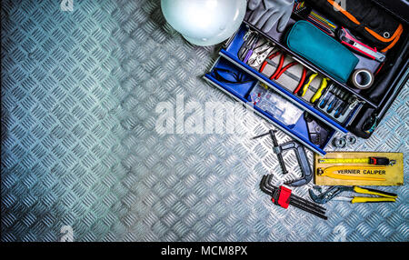 Top view of tools box and helmet on checkered plate background in workshop. Service tools set. Home building and electrical tools. Plumber hand tools. Stock Photo