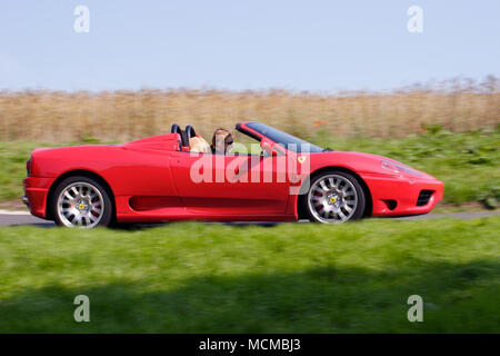 Profile (side view) of a Red Ferrari 360 Spider super car sportscar driving fast. Stock Photo
