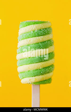 Yellow and green spiral ice cream on a colorful background. Stock Photo