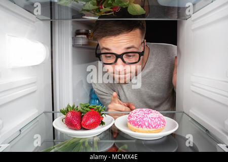 Man choosing between fruits and candy Stock Photo