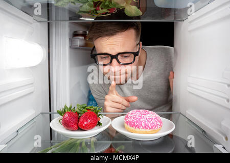 Man choosing between fruits and candy Stock Photo