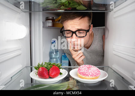 Man choosing between fruits and candy Stock Photo