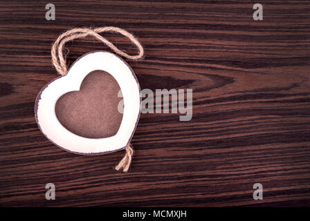Photo frame in wood heart shape on wenge wood background. Stock Photo