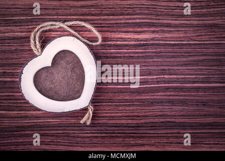 Photo frame in wood heart shape on palisander wood background. Stock Photo
