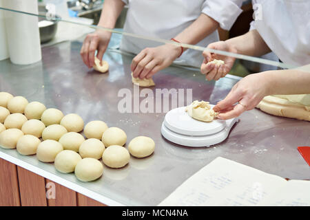 Confectioners bakers cook dough for buns on bakery table Stock Photo