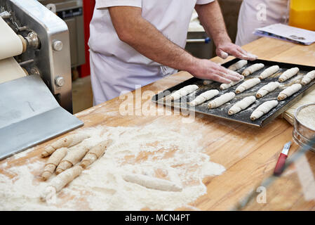 Confectioners bakers cook dough for roll buns on bakery table Stock Photo