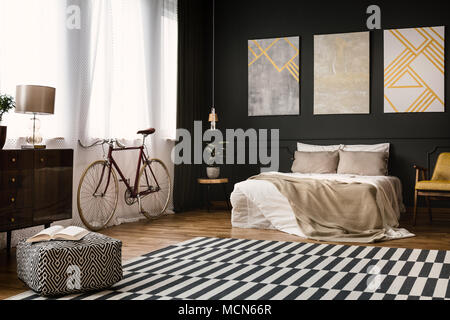 Vintage room interior with bed, bike, carpet on the floor and pouf Stock Photo