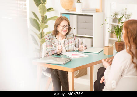 Smiling personal advisor talking to a client in her light, cozy office Stock Photo