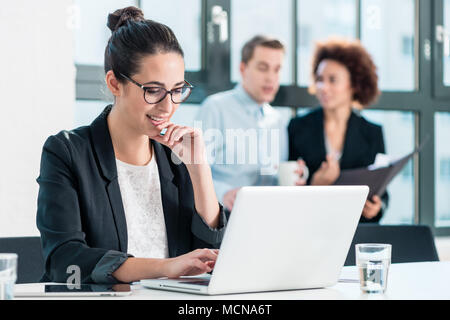 Young woman smiling while using a laptop in the office Stock Photo
